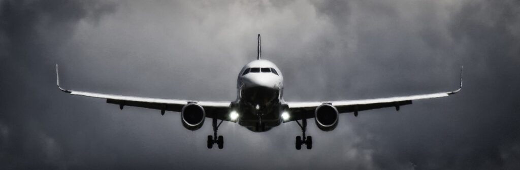A dramatic view of an airplane landing with stormy clouds overhead, showcasing aviation in a monochrome scene.